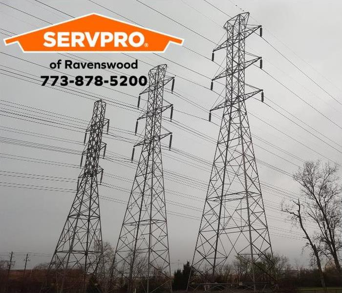 Three tall power towers with several power lines with a grey sky in the background.
